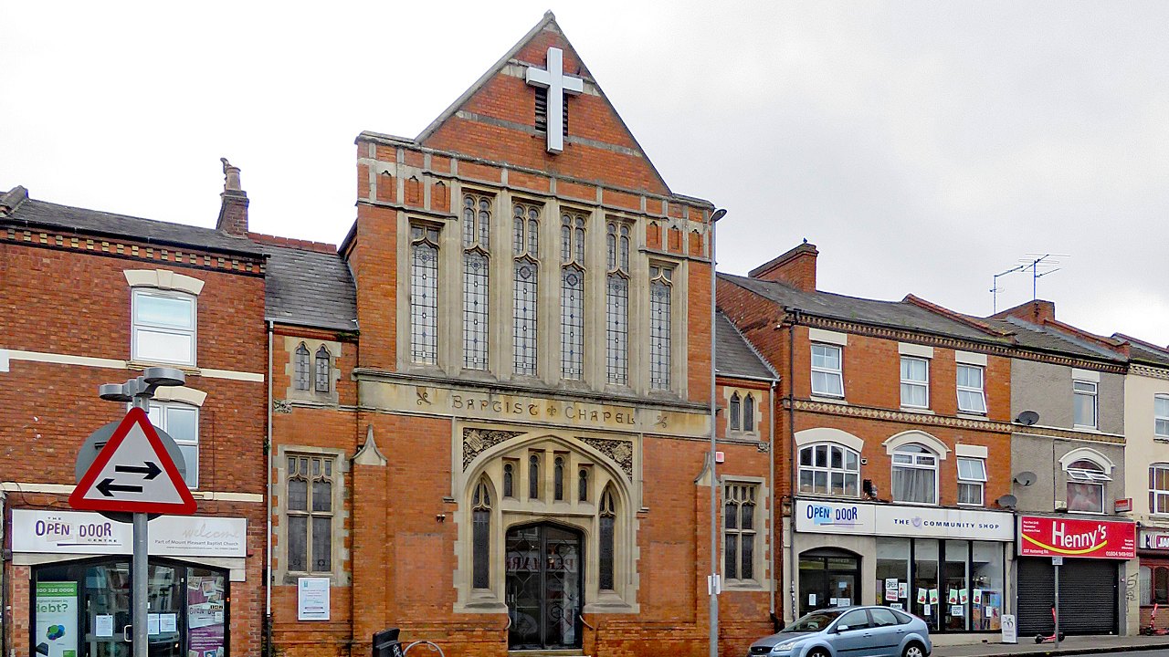 The chapel seen across Kettering Road, with the Open Door Centre and shops alongside it
